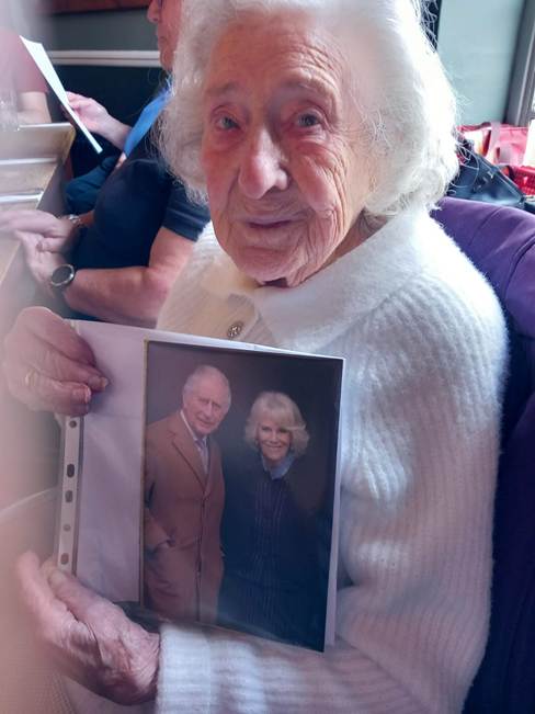 An old person holding a photo of two people

Description automatically generated